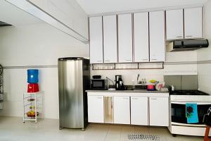 a kitchen with white cabinets and a stainless steel refrigerator at 0001 - Pousada HG quarto home office, duplo in Vila Gopoúva +9 photos