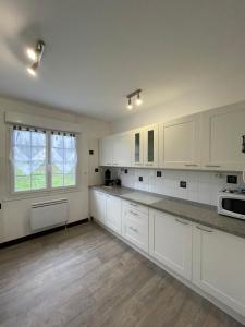une cuisine vide avec des placards blancs et une fenêtre dans l'établissement Maison des Rêves de Loire, à Saint-Aignan