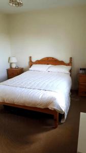 a bedroom with a large bed with white sheets and pillows at 3BedHouse-Ballyliffin-NearBeach-GolfCourses nearby in Ballyliffin