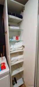 a closet filled with white towels and a shelf at Sweet Home in Dimona