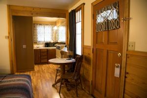 Habitación con mesa y cocina con puerta. en Sleepy Forest Cottages en Big Bear Lake