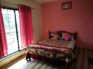 a bedroom with a bed with red walls and a window at Patankar Nest Homestay in Helwāk