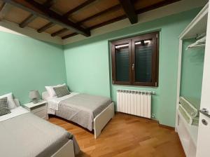 Una pequeña habitación con dos camas y una ventana. en Casa Palanca, en Stia