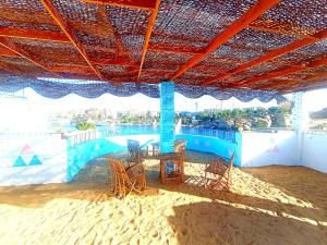 a group of chairs and tables under an umbrella on a beach at Winji Guest house in Aswan
