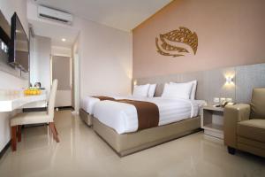 a hotel room with a large bed and a chair at Gets Hotel in Malang