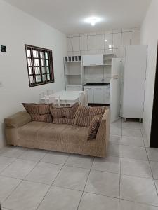 a living room with a couch and a kitchen at Bela casa de praia in Palhoça