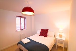 a bedroom with a bed with a red pillow on it at Andover Charming Three Bedroom House in Andover