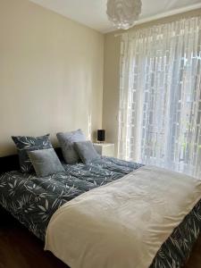 ein Bett in einem Schlafzimmer mit einem großen Fenster in der Unterkunft Villa Quintel -Proche gare & centre -JardinBalcon in Brive-la-Gaillarde