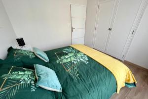 ein Schlafzimmer mit einem grünen Bett mit Kissen in der Unterkunft Villa Quintel -Proche gare & centre -JardinBalcon in Brive-la-Gaillarde