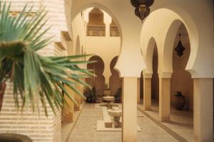 a hallway of a building with arches and a plant at Sahara pearl Hotel in Merzouga