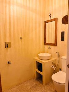 a bathroom with a sink and a toilet and a mirror at San-Khara in Ahangama