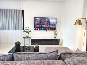 a living room with a couch and a tv on the wall at Villa Coco - Tropical Paradise with Private Pool in Thalang