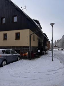 a car parked next to a building in the snow at Apartmán Mirka Dolní Morava in Dolní Morava +2 photos