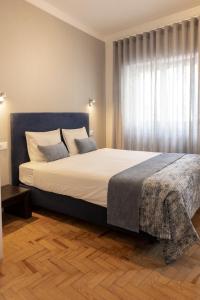 una camera da letto con un letto grande con una grande finestra di Casa das Aguarelas - Apartamentos a Ericeira