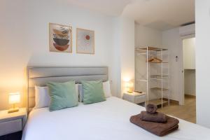 Un dormitorio con una cama blanca con un osito de peluche encima. en Jome Stays Alicante centro, en Alicante