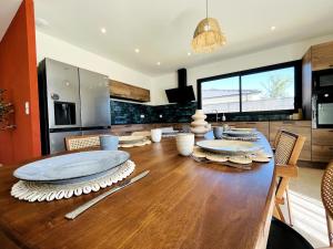 a dining room with a wooden table with plates on it at Villa exotique avec piscine - Dolce Rhôna in Charmes-sur-Rhône