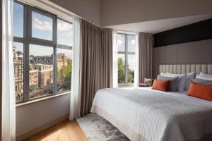 ein Schlafzimmer mit großem Bett und großen Fenstern in der Unterkunft Anantara Grand Hotel Krasnapolsky Amsterdam in Amsterdam