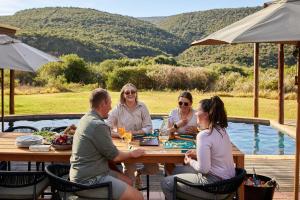 a group of people sitting around a wooden table at Kwandwe Private Game Reserve - Melton Manor in Grahamstown
