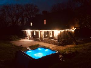 a house with lights around a swimming pool at night at Maison rénovée - jacuzzi et cheminée in Saint-Samson-de-la-Roque