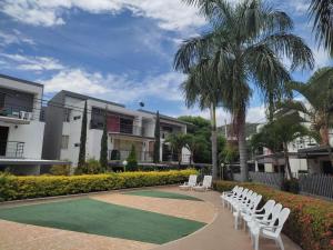 een rij witte tuinstoelen en een palmboom bij Apartasol Familiar 2 in Santa Fe de Antioquia