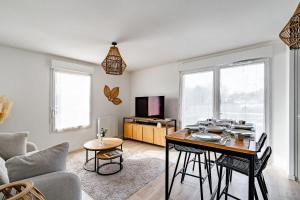 una sala de estar con una mesa y un sofá en Le souffle de Vendays - Appt avec jardin, en Vendays-Montalivet