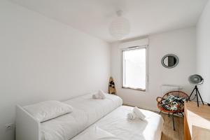 una sala de estar blanca con 2 sofás blancos y una ventana en Le souffle de Vendays - Appt avec jardin, en Vendays-Montalivet