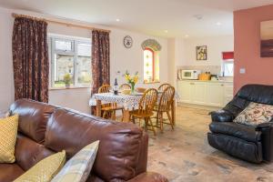 a living room with a leather couch and a table at Cothi Cottage in Cardigan