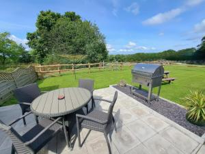 a patio with a barbecue and a table and chairs at Cothi Cottage in Cardigan