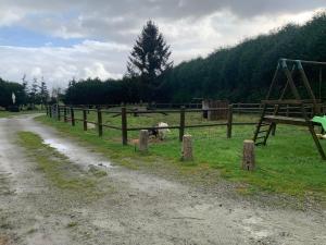 a dirt road next to a fence with a playground at Gîte le parc Michel in Roz-sur-Couesnon