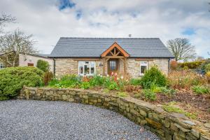 une maison en pierre avec un mur en pierre et des fleurs dans l'établissement Gwaun Cottage, à Cardigan