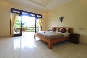 a bedroom with a bed and a large sliding glass door at Frangipani Bungalow in Ubud
