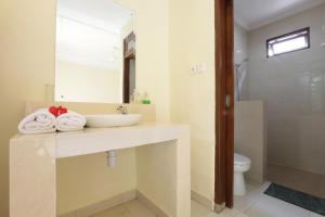 bagno con lavandino, servizi igienici e specchio di Frangipani Bungalow ad Ubud