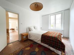 une chambre blanche avec un lit et une fenêtre dans l'établissement Le Presbytère, maison de campagne familiale, à La Poterie-au-Perche