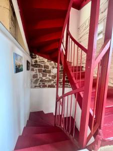 eine rote Wendeltreppe in einem Haus mit einer Steinmauer in der Unterkunft Grande Maison pour 8 personnes - Bourg de Meyssac in Meyssac