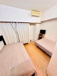 a small room with two beds and a tv at Shinjuku West Park Inn Hanabi House in Tokyo +9 photos