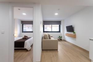 Un dormitorio con una cama, un sofá y un televisor. en Jome Stays Alicante centro, en Alicante