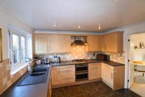 a kitchen with wooden cabinets and a stove top oven at Warfield Charming Three Bedroom House in Warfield