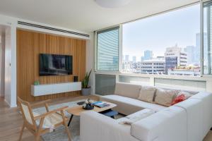 a living room with a white couch and a large window at Mate Kalischer - By HOMY in Tel Aviv