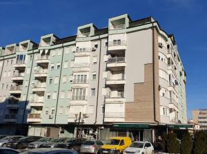 a tall building with cars parked in front of it at Apartman KIKA in Banja Luka