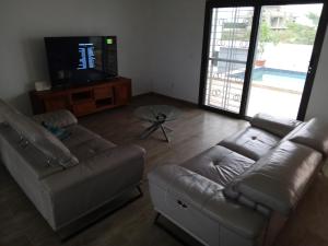Una sala de estar con un sofá y un televisor. en Villa 2 chambres salon piscine saly, en Mbour 4 fotos más