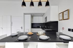 eine Küche mit weißen Schränken sowie einem schwarzen Tisch und Stühlen in der Unterkunft Suite New Delhi - Superbe Appartement in Suresnes + 10 Fotos