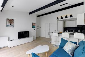 ein Wohnzimmer mit einer blauen Couch und einer Küche in der Unterkunft Suite New Delhi - Superbe Appartement in Suresnes