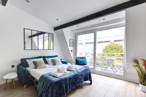 ein Schlafzimmer mit einem blauen Bett und einem großen Fenster in der Unterkunft Suite New Delhi - Superbe Appartement in Suresnes