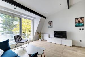 ein Wohnzimmer mit Sofa und Fernseher in der Unterkunft Suite New Delhi - Superbe Appartement in Suresnes