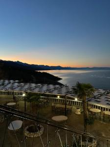 a resort with tables and chairs and a view of the water at Hotel Panorama Zogaj in Zogaji