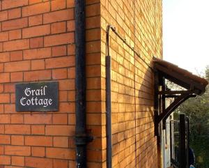 a sign on the side of a brick building at Grail Cottage in Glastonbury