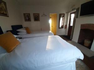 a bedroom with two large white beds in it at Grail Cottage in Glastonbury +7 photos