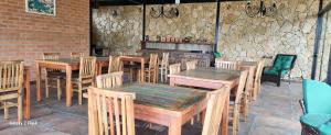 a restaurant with wooden tables and chairs and a stone wall at Pousada Maria Irani in São Roque