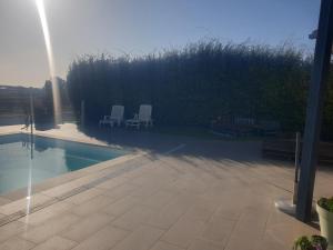 two white chairs sitting next to a swimming pool at Chambre d'hôte avec accès piscine in Gigean +2 photos