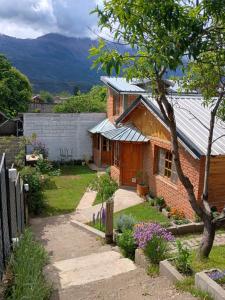 a brick house with a metal roof in a yard at Alojamiento Puesta del Sol in El Bolsón